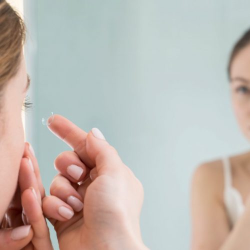 Woman in front of a mirror putting in a contact lens